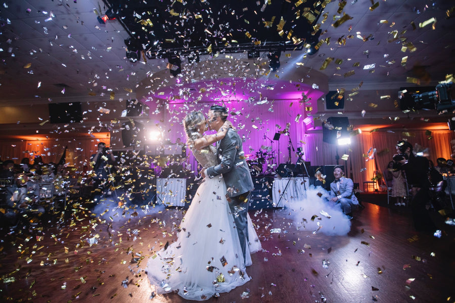 Couple posing at a wedding while silver confetti falls all around them.