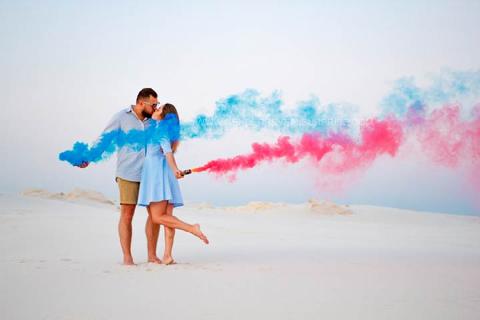 Couple posing with pink and blue smoke cannons on a beach