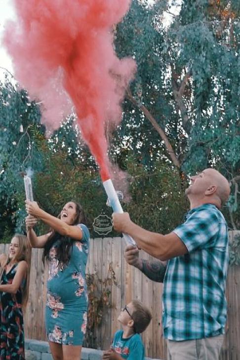 Couple posing while shooting pink smoke cannons into the air.