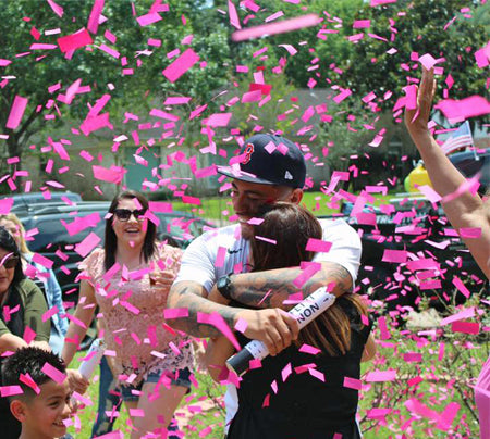 Couple hugging outside with pink confetti all aroud them