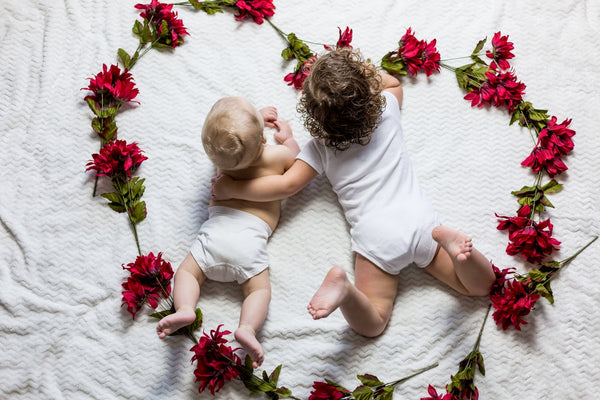 infant siblings posing in the middle of a flower circle