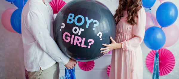 Couple holding a gender reveal balloon that says 