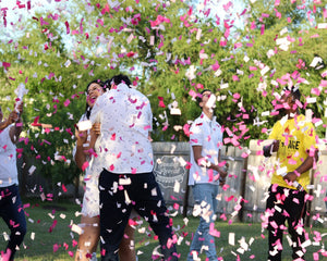 Couple hugging joyfully as they are showered with pink gender reveal confetti cannons